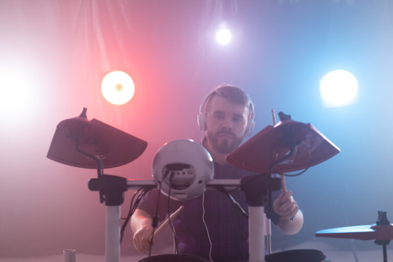 Music, interests, hobby and people concept - young man playing the electronic drums